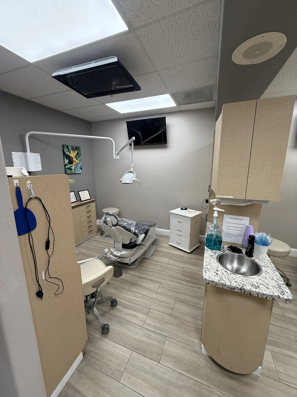 Treatment room with a dental chair, exam light, and cabinetry